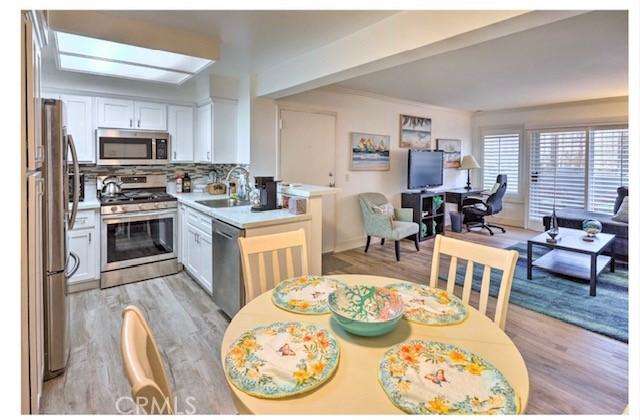 kitchen featuring light hardwood / wood-style flooring, appliances with stainless steel finishes, sink, and white cabinets