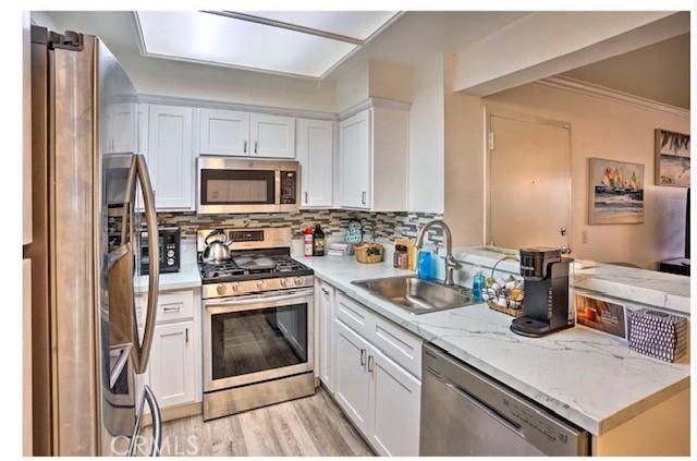 kitchen featuring white cabinets, stainless steel appliances, sink, and backsplash