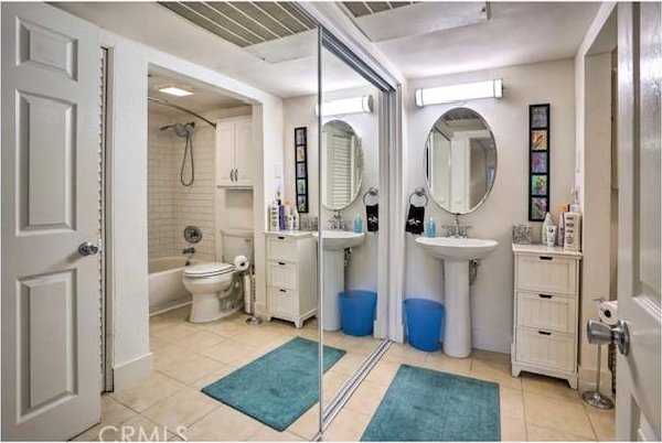 bathroom with toilet, tiled shower / bath combo, and tile patterned floors