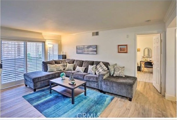 living room with ornamental molding and light wood-type flooring