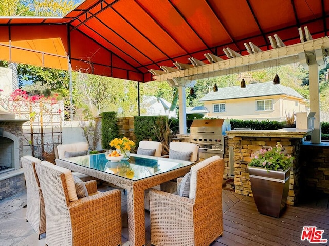 wooden deck featuring area for grilling, a pergola, grilling area, and an outdoor stone fireplace