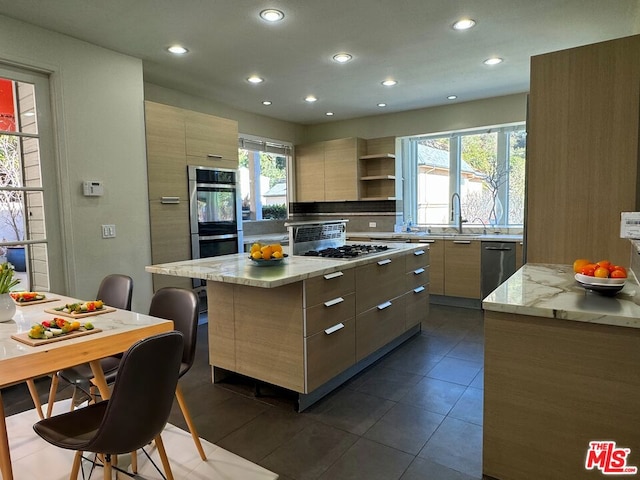 kitchen with a breakfast bar, light brown cabinetry, sink, a center island, and stainless steel appliances