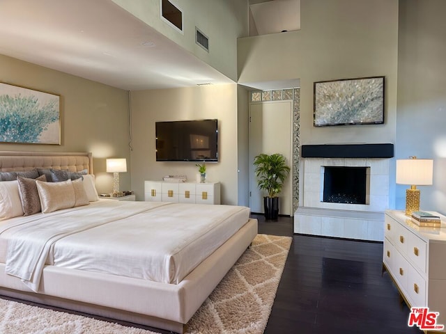 bedroom featuring dark hardwood / wood-style floors and a tiled fireplace