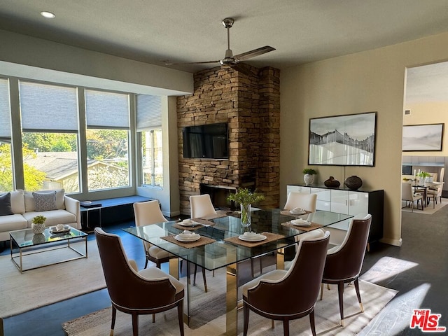 dining room with ceiling fan, wood-type flooring, a fireplace, and a textured ceiling