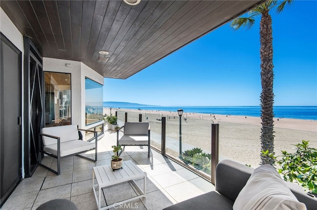 balcony featuring outdoor lounge area, a water view, and a beach view