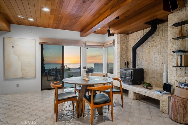 tiled dining area featuring wood ceiling, a wood stove, and beamed ceiling