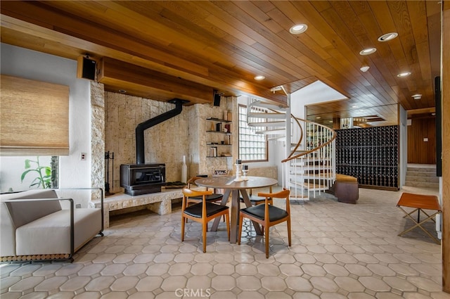 dining space with wood ceiling, a wood stove, and beam ceiling