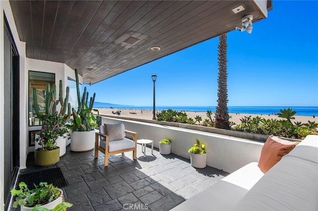 view of patio featuring a view of the beach, a water view, and a balcony