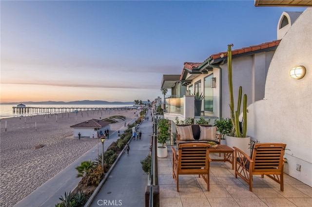 balcony at dusk with a water and mountain view and outdoor lounge area