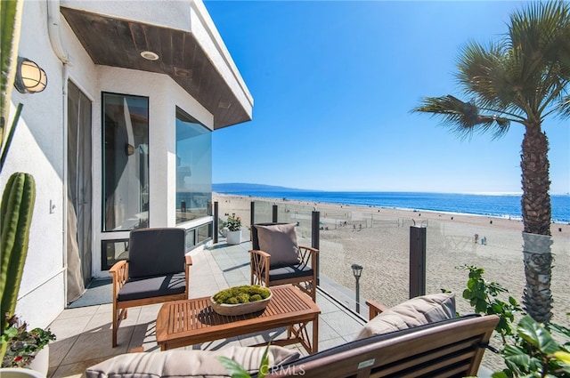 balcony featuring outdoor lounge area, a view of the beach, and a water view