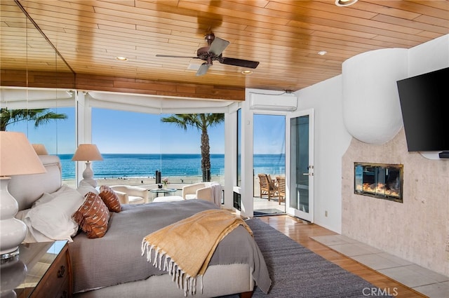 bedroom featuring hardwood / wood-style floors, a wall mounted AC, wood ceiling, and a water view