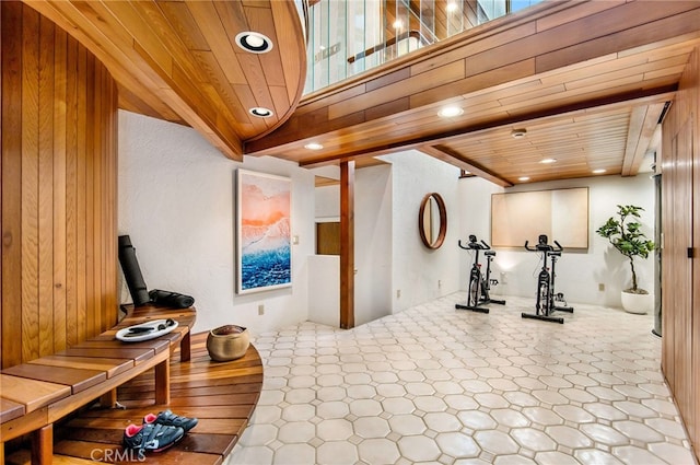 exercise room featuring vaulted ceiling, wood ceiling, and wood walls