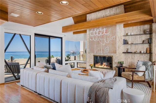 living room featuring light hardwood / wood-style flooring, wood ceiling, a fireplace, and a water view