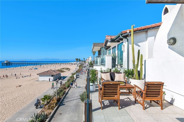 view of patio with an outdoor hangout area, a water view, and a beach view