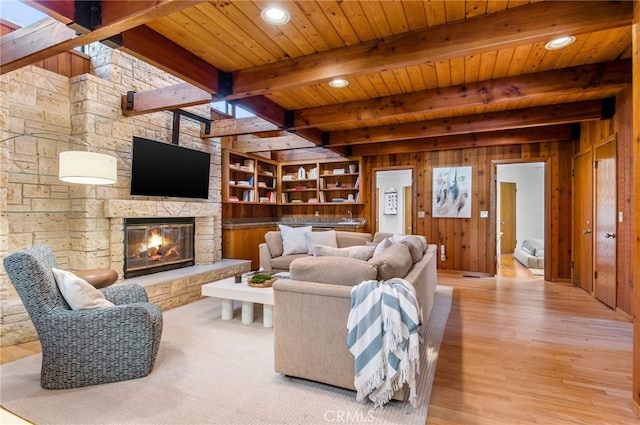 living room with wood ceiling, beam ceiling, wooden walls, light hardwood / wood-style flooring, and a fireplace