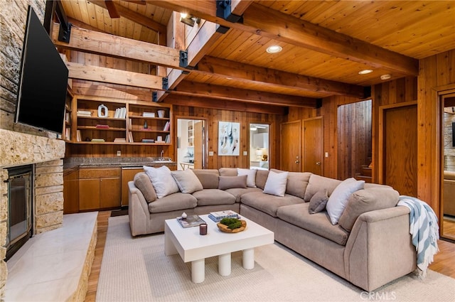 tiled living room featuring beam ceiling, a stone fireplace, wooden ceiling, and wood walls