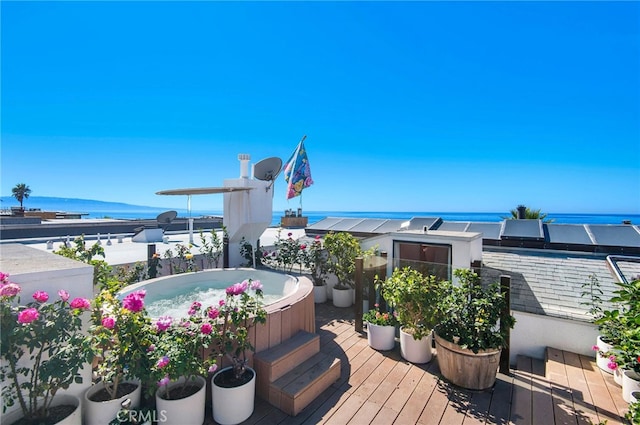 wooden deck with a hot tub and a water view