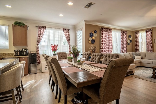 dining space with crown molding, light hardwood / wood-style floors, and plenty of natural light