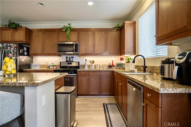 kitchen featuring light wood-type flooring, stainless steel appliances, sink, crown molding, and light stone counters