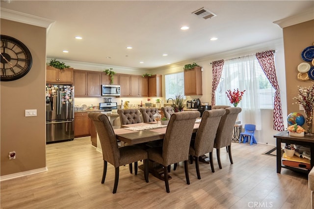 dining space with crown molding and light hardwood / wood-style flooring