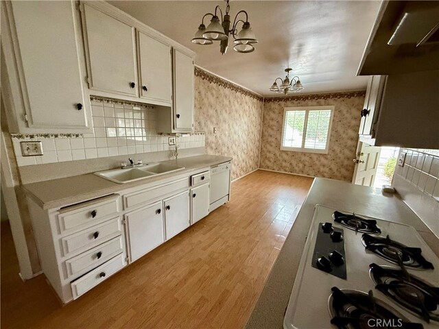 kitchen featuring hanging light fixtures, white cabinets, a chandelier, and white appliances