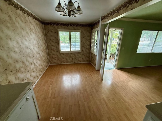 unfurnished room with an inviting chandelier, light hardwood / wood-style flooring, a healthy amount of sunlight, and crown molding