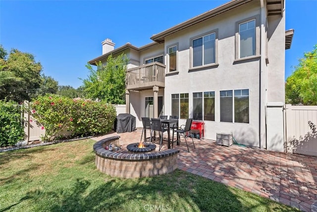 back of property featuring a balcony, a yard, and a patio