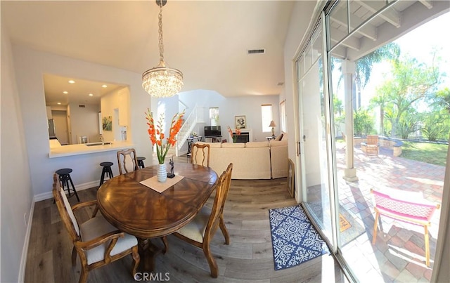 dining space with sink, wood-type flooring, and a chandelier