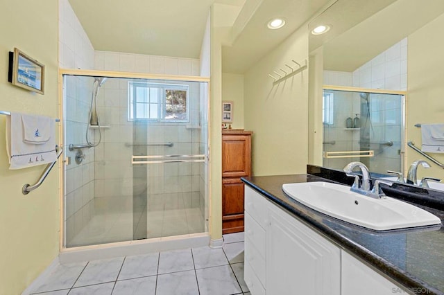 bathroom with a shower with shower door, vanity, and tile patterned floors