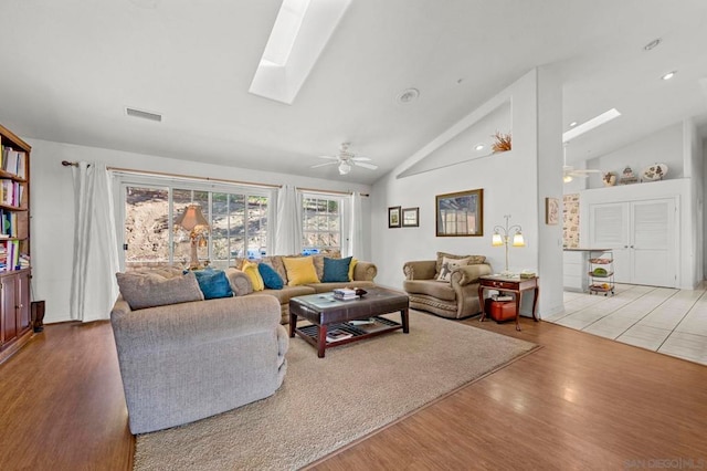 living room with ceiling fan, hardwood / wood-style floors, high vaulted ceiling, and a skylight