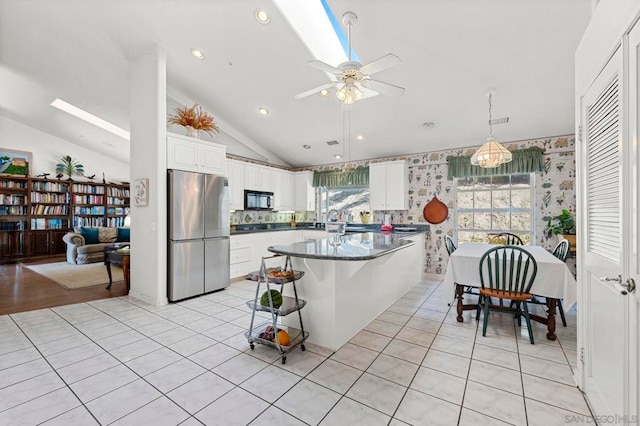 kitchen with light tile patterned floors, white cabinetry, stainless steel fridge, lofted ceiling, and a breakfast bar