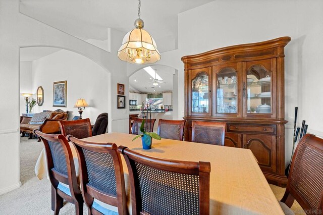 carpeted dining area featuring ceiling fan with notable chandelier