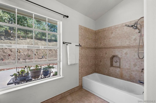 bathroom with vaulted ceiling, tiled shower / bath combo, and tile patterned flooring