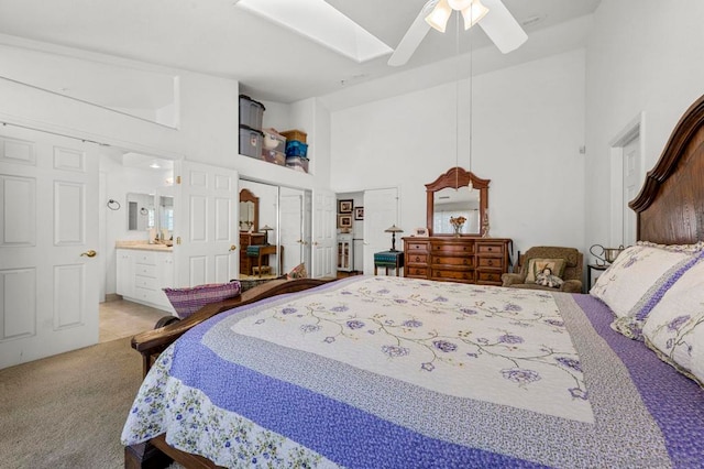 bedroom with a high ceiling, a closet, ceiling fan, light colored carpet, and ensuite bathroom