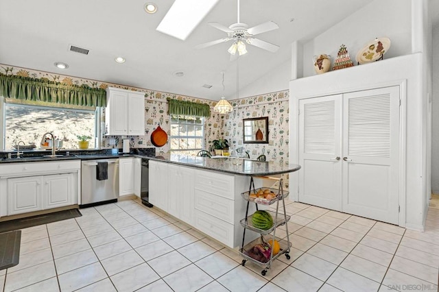 kitchen with vaulted ceiling with skylight, dishwasher, kitchen peninsula, sink, and white cabinetry