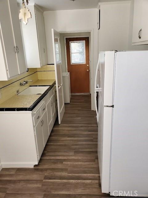 kitchen featuring white cabinets, white refrigerator, sink, and dark wood-type flooring