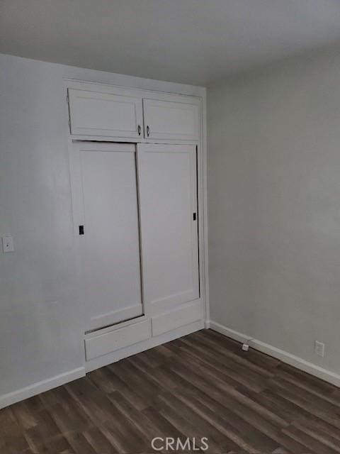 unfurnished bedroom with dark hardwood / wood-style floors and a closet