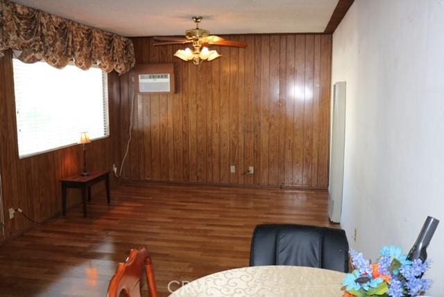 dining area featuring a wall mounted air conditioner, dark hardwood / wood-style flooring, ceiling fan, and wood walls