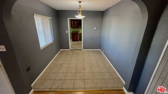 hallway featuring a textured ceiling and light tile patterned floors