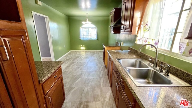 kitchen featuring decorative light fixtures, a chandelier, sink, and dark stone counters