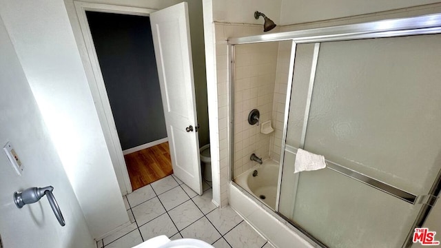 bathroom with toilet, tile patterned floors, and shower / bath combination with glass door