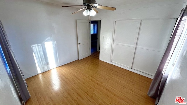 unfurnished bedroom featuring wood-type flooring, a closet, and ceiling fan