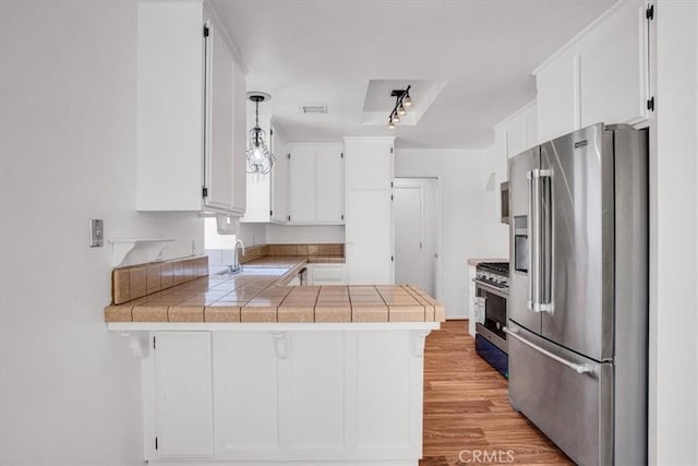 kitchen featuring kitchen peninsula, premium appliances, light hardwood / wood-style flooring, and white cabinetry