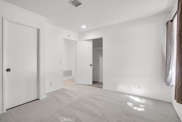 unfurnished bedroom featuring light carpet and a closet