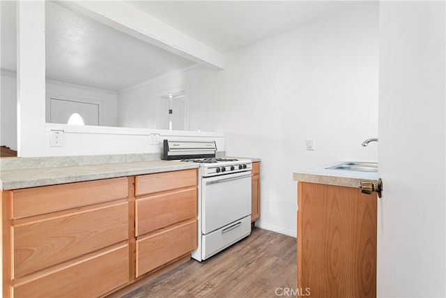 kitchen with white range with gas cooktop, beam ceiling, dark hardwood / wood-style flooring, crown molding, and sink