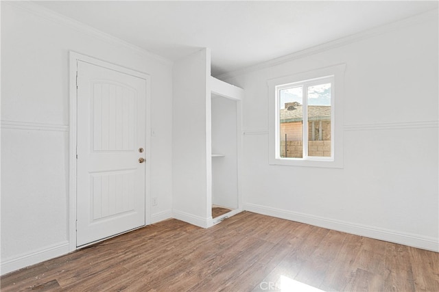 empty room with ornamental molding and wood-type flooring