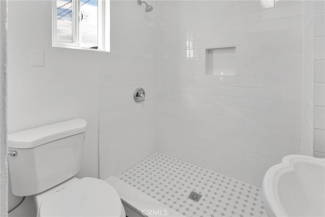 bathroom with a tile shower and toilet