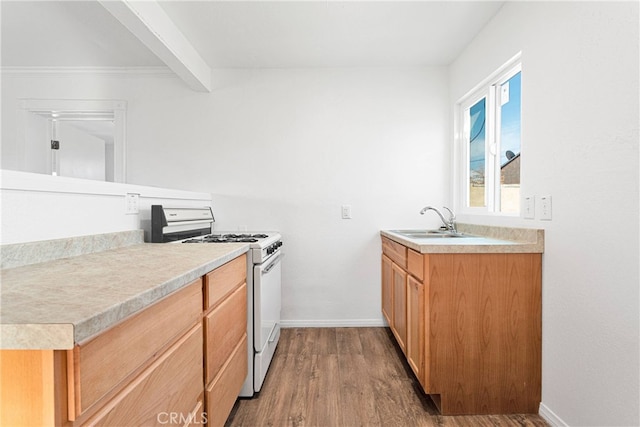 kitchen featuring white range with gas cooktop, beam ceiling, hardwood / wood-style flooring, and sink