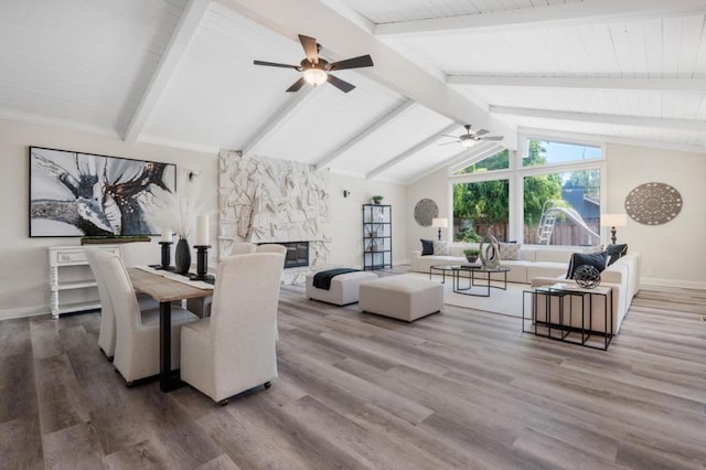 living room featuring vaulted ceiling with beams, a stone fireplace, ceiling fan, and hardwood / wood-style flooring