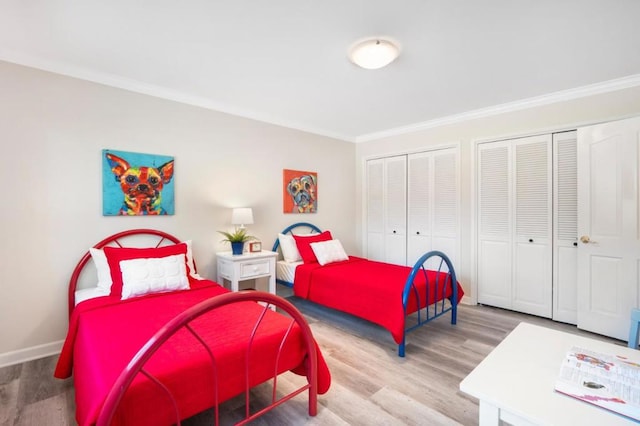 bedroom featuring multiple closets, wood-type flooring, and crown molding